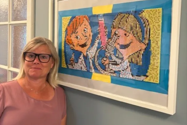 Jessica Melin står vid en tavla med Ville och Vilma. Foto.