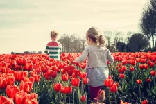 Två barn ute på ett fält med tulpaner. Foto.